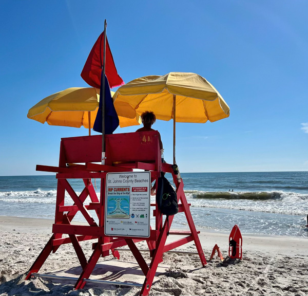 lifeguard sitting on chair watching beachgoers