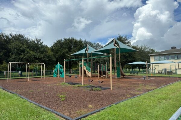 A playground with swing sets and big and small play structures for children.