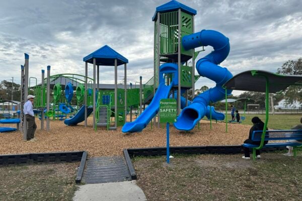 Parents watch children play aorund the slide at a playground.