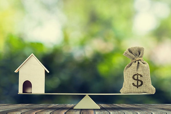 house balanced in a seesaw with bag of money