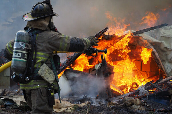 firefighter aiming hose at burning structure