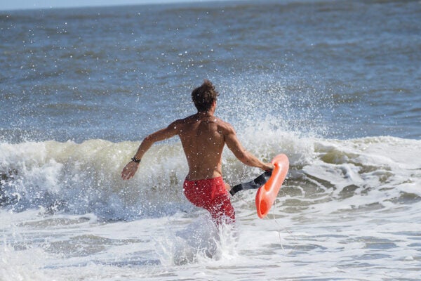 lifeguard running into water with flotation device