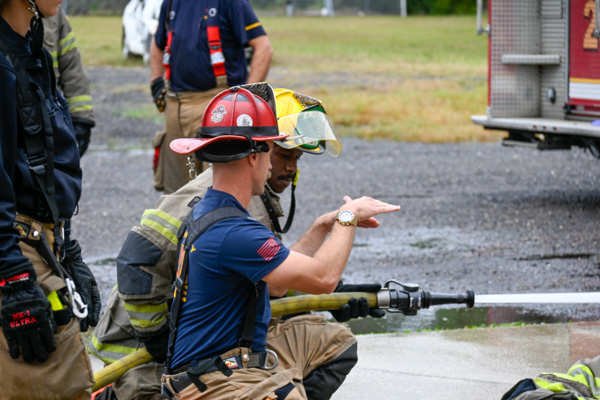 firefighter showing trainee how to spray water
