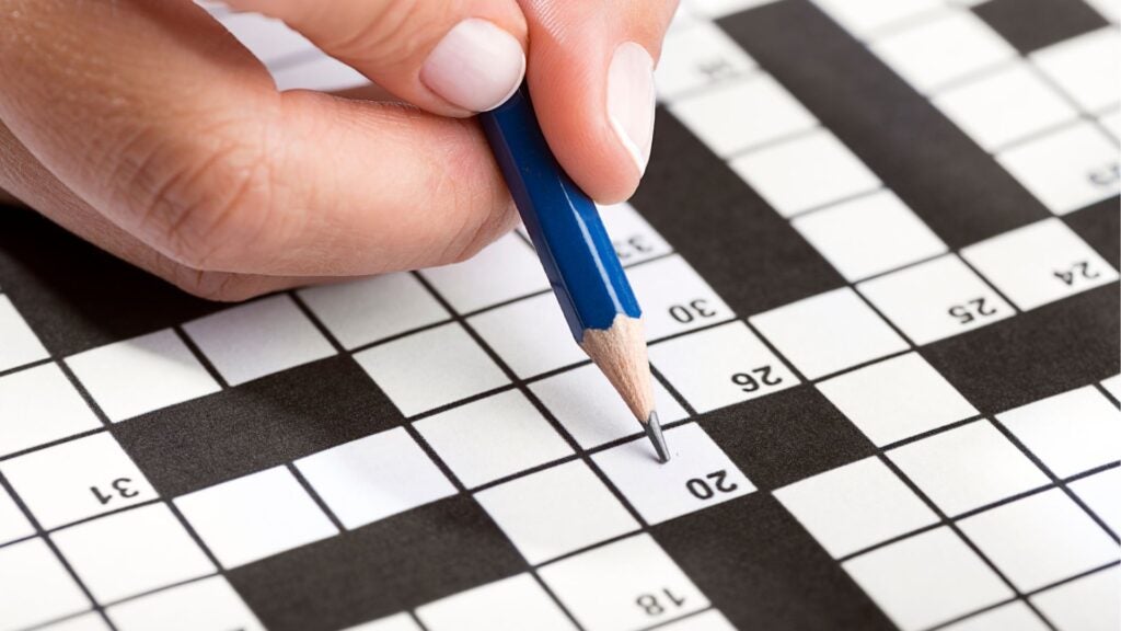 crossword puzzle and a hand holding a pencil