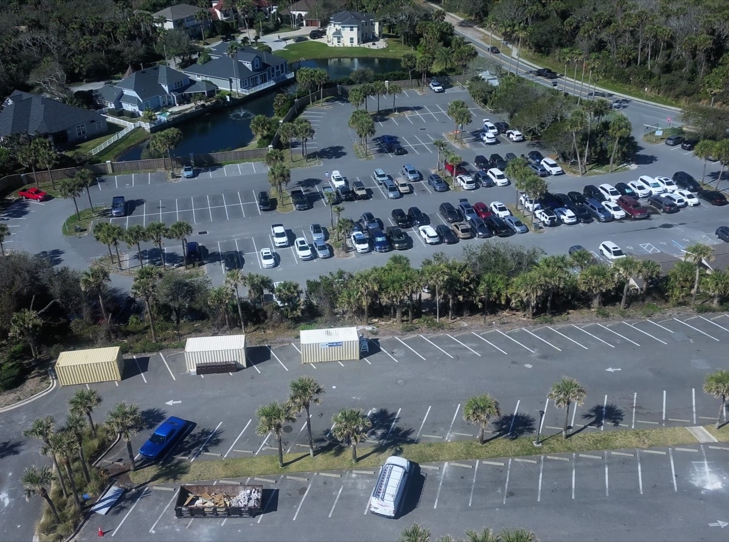 Overhead view of a parking lot partly filled with cars.