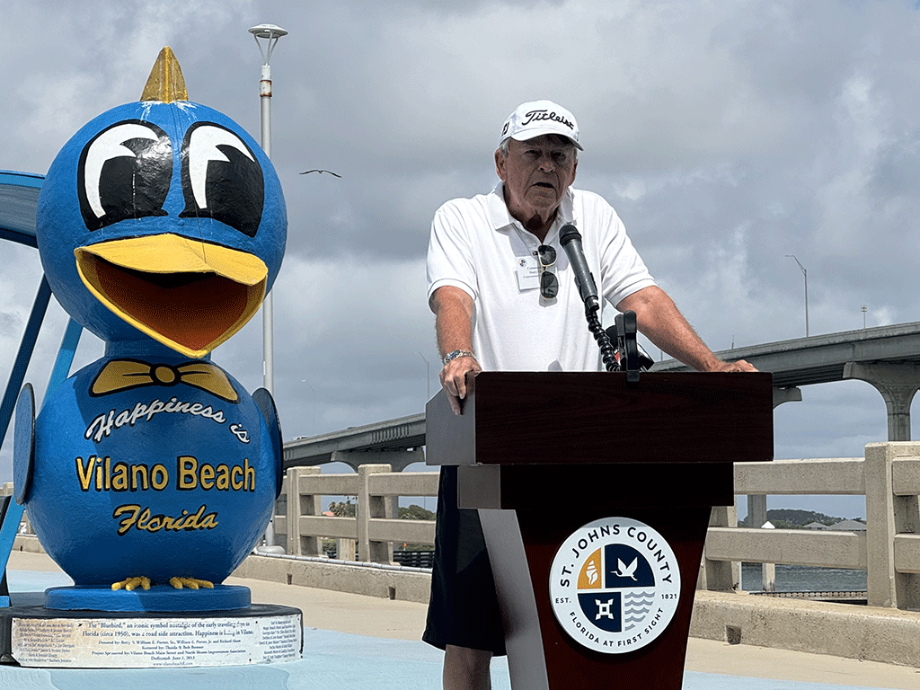 St. Johns County District 5 Commissioner, Henry Dean speaking at Vilano Beach Pier with Vilano Mascot statue and bridge in background
