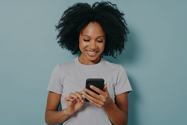 woman smiling while looking down at phone