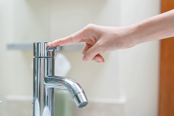 A person is turning off the water tap.