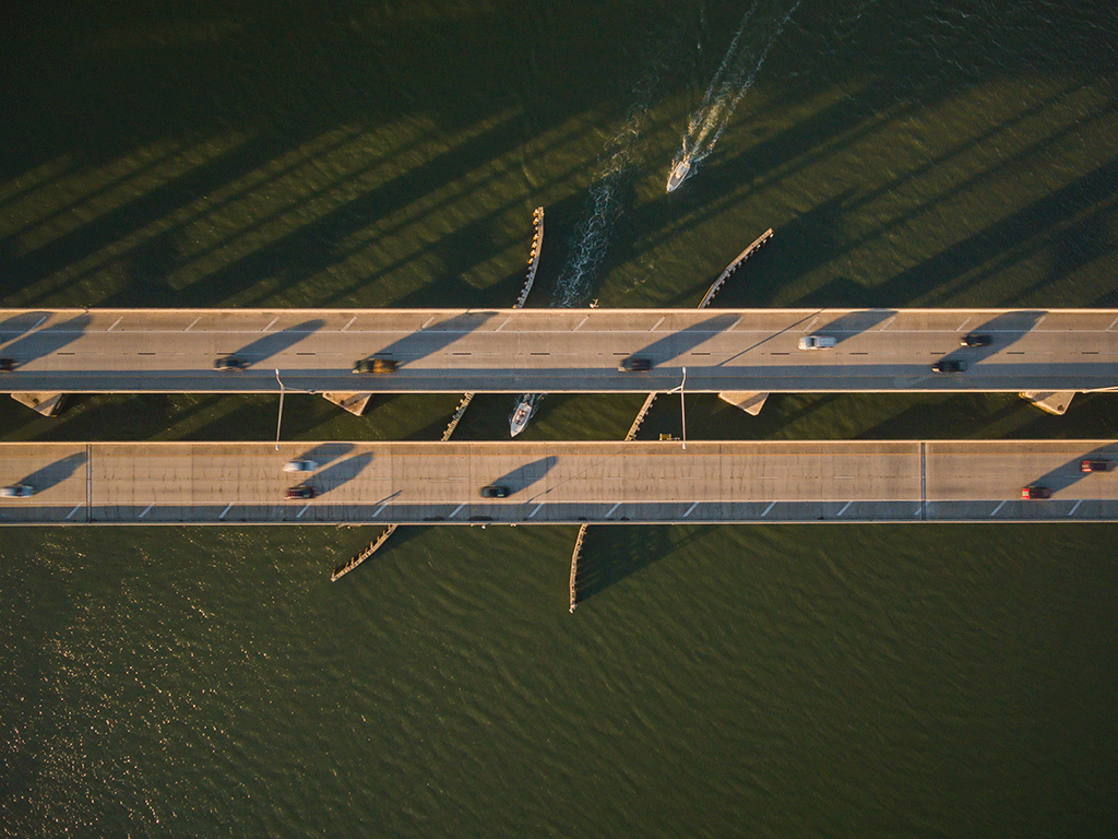 aerial of boats passing under bridge
