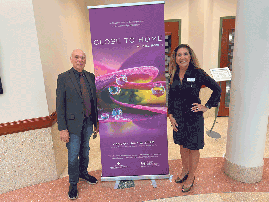 Commissioner Taylor stands in front of a Close to Home sign, the April 9 to June 5 Art in Public Spaces exhibit.