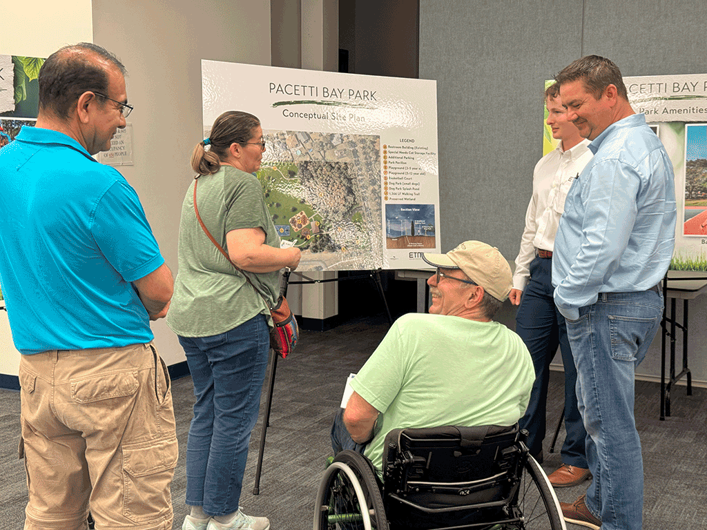 Citizens talk to each other in front of a Pacetti Bay Park Conceptual Site Plan poster.