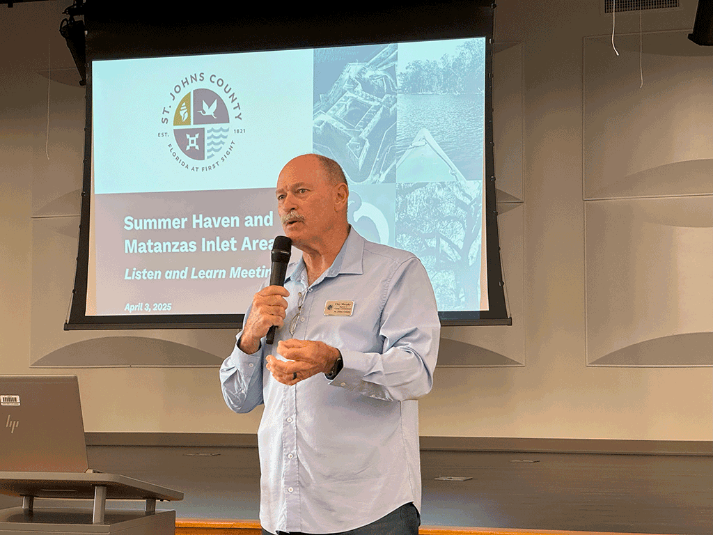 Commissioner Clay Murphy talks into a microphone in front of a presentation reading "Summer Haven and Matanzas Inlet Area Listen and Learn Meeting"