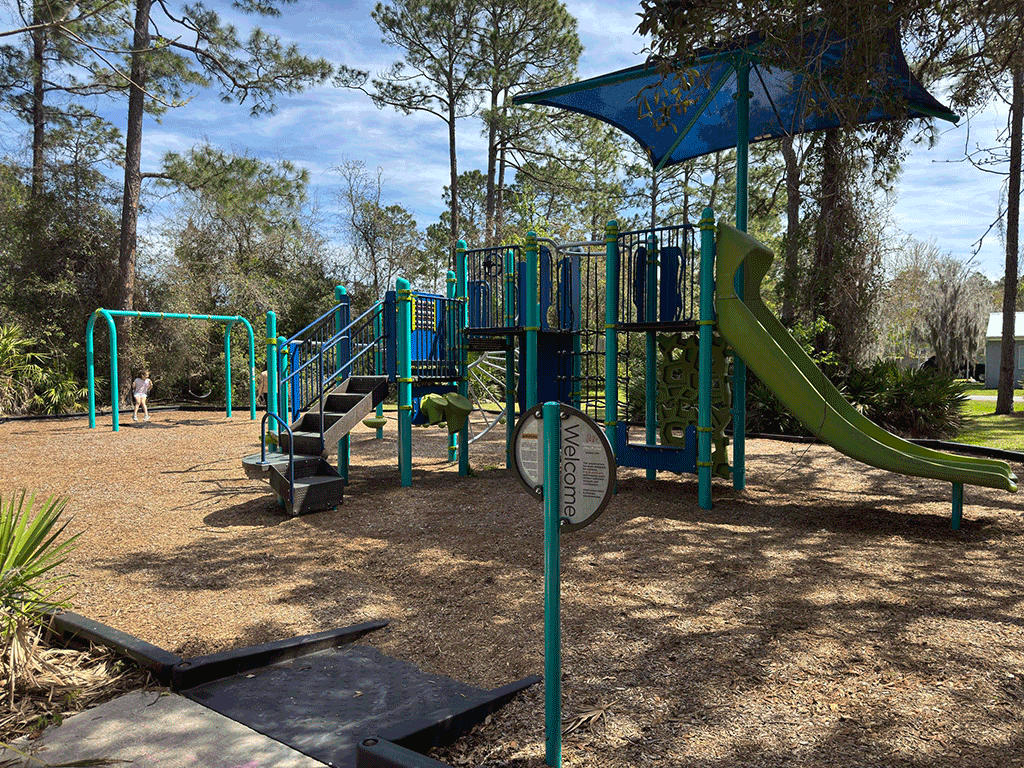 A shaded playground with a young girl on a swingset.