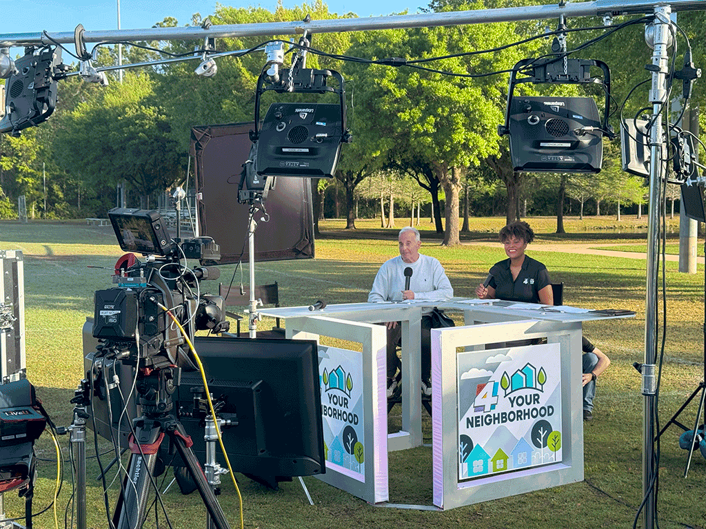 A camera is focused on a news anchor at a desk labeled "4 Your Neighborhood" outside.