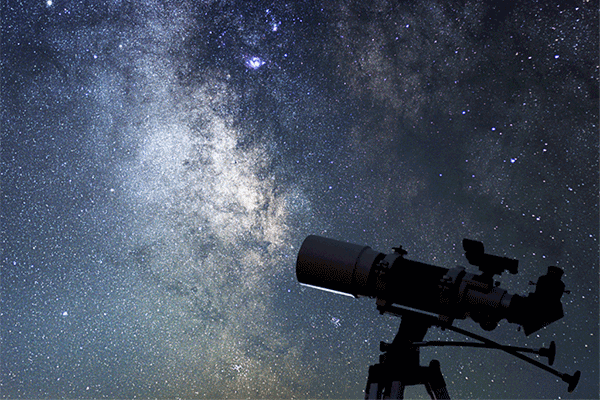 A telescope pointed upward at a starry night sky.