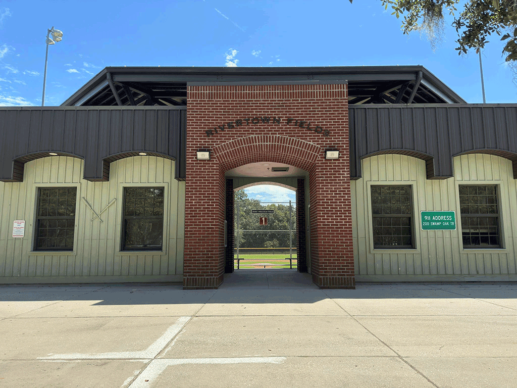 The brick exterior of a baseball complex with letters spelling ‘Rivertown Fields.’