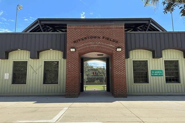 The brick exterior of a baseball complex with letters spelling ‘Rivertown Fields.’