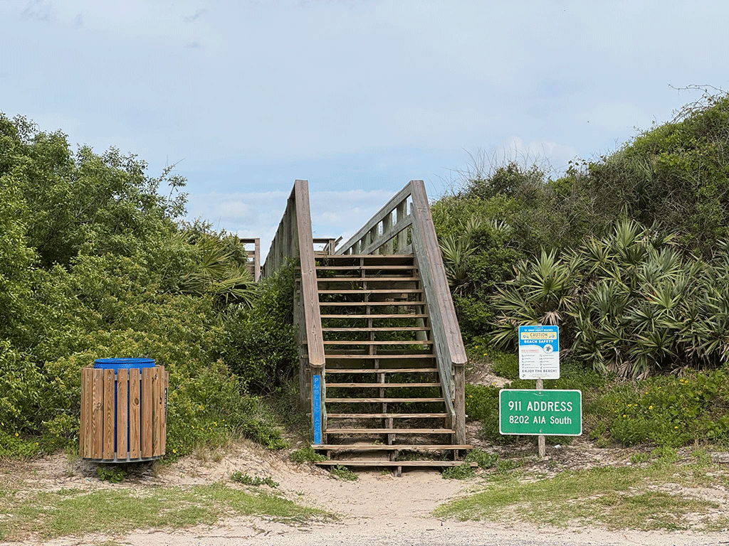 A wooden staircase leading over dunes to the beach.