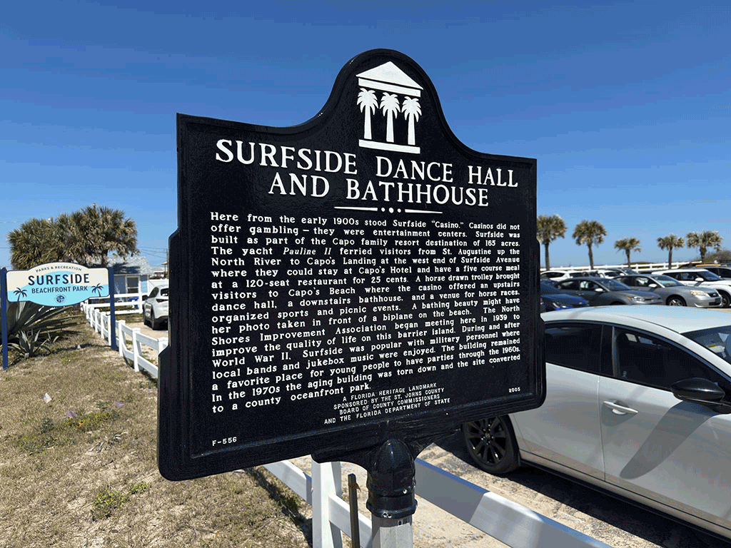A historical marker next to a parking lot, recounting the story of the Surfside Dance Hall and Bathhouse.