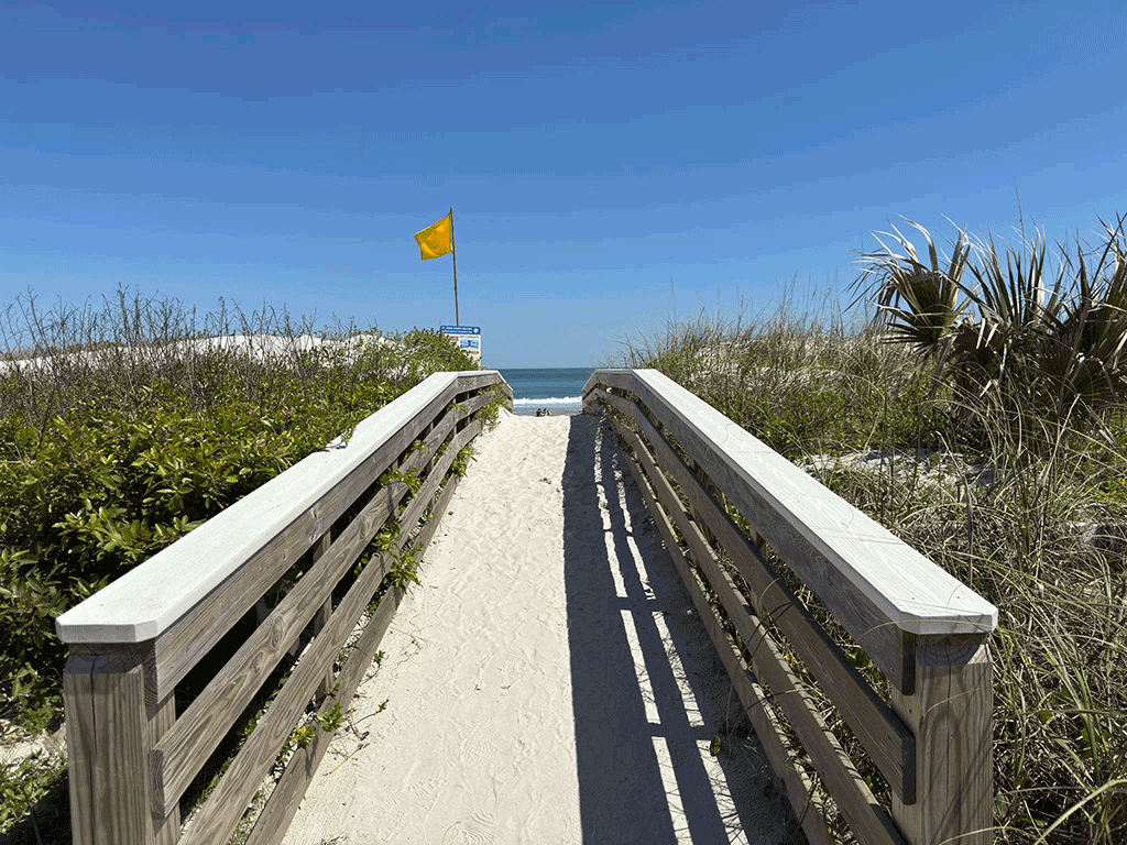 A wooden walkway leading over dunes to the beach.