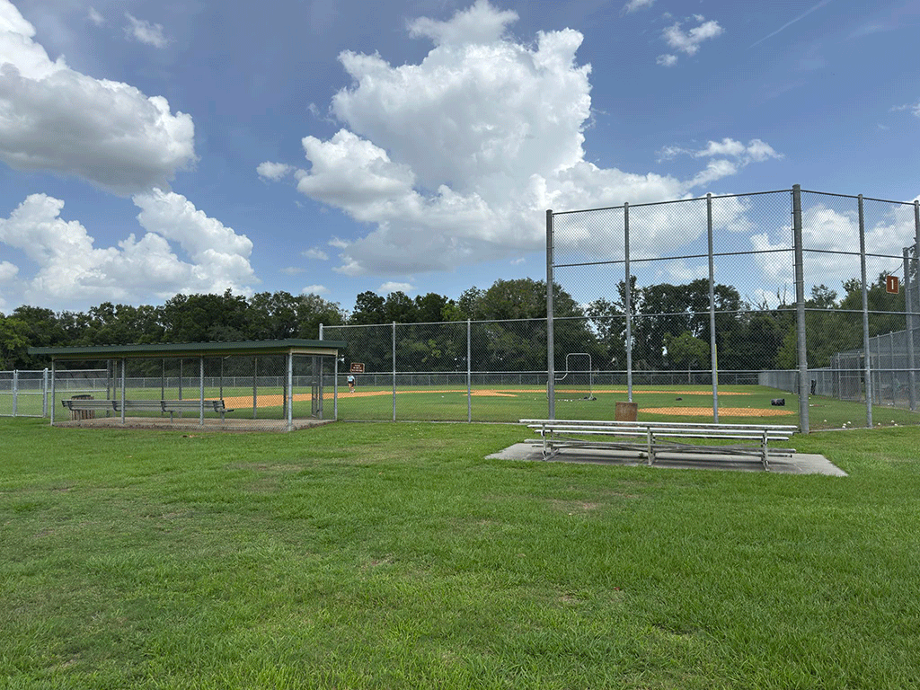A fenced-in baseball field with seats for spectators and players.