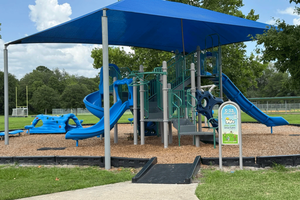 A park playground with climbing structures and a covered play area with slides.