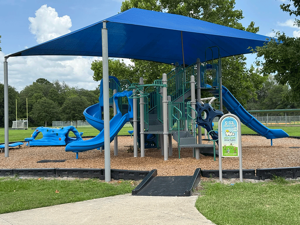 A park playground with climbing structures and a covered play area with slides.