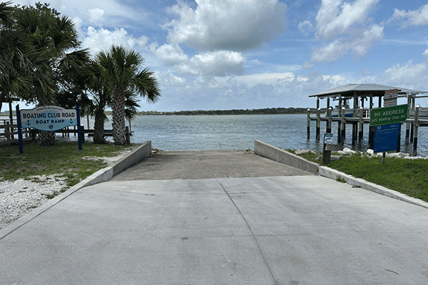 A concrete boat ramp into the Intracoastal, with boat docks on either side and a sign marking it as the Boating Club Road Boat Ramp.