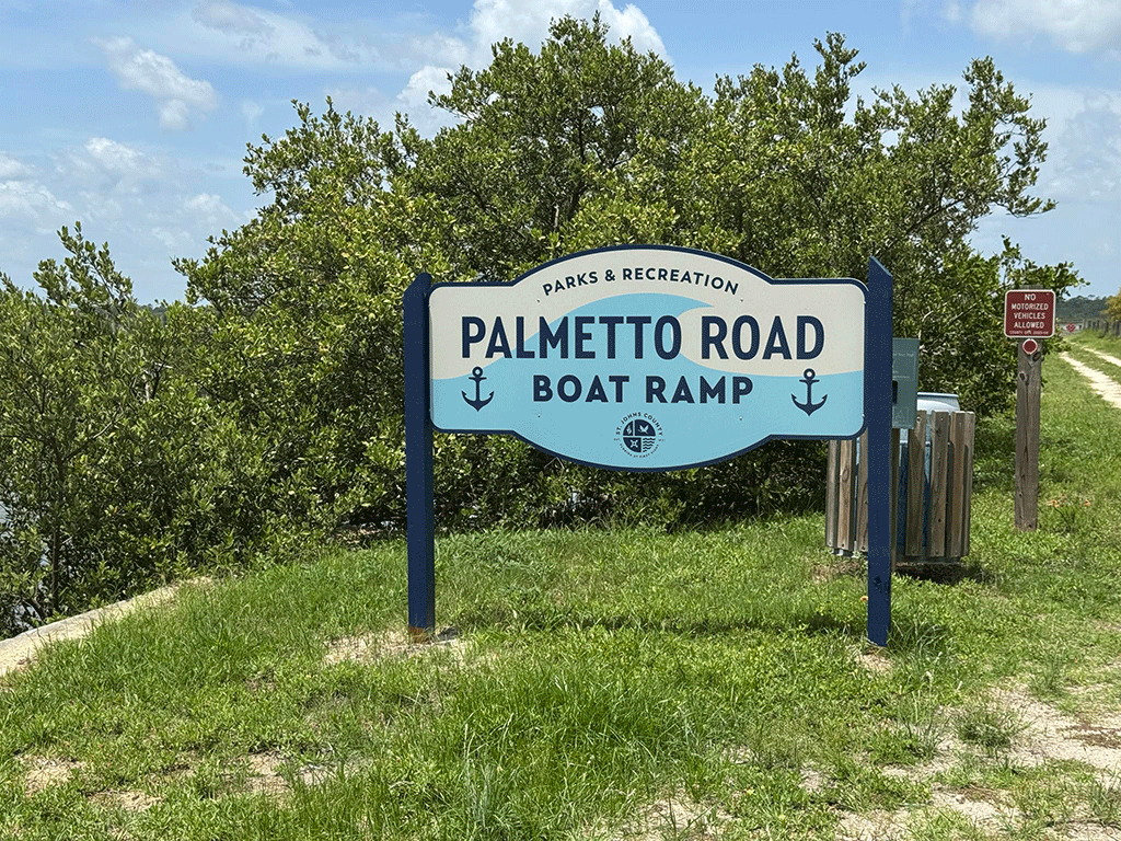 A sign for the Palmetto Boat Ramp in front of some bushes