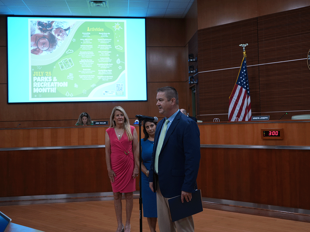 Parks and Recreation Director Ryan Kane speaks at a microphone while Parks and Recreation Assistant Director Jamie Baccari and District 4 Commissioner/Board Chair Krista Joseph watch