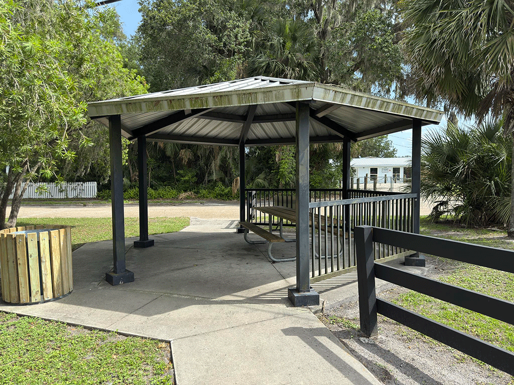 A small covered pavilion over a picnic table on a street corner