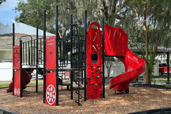 A small streetside playground in front of a covered pavilion