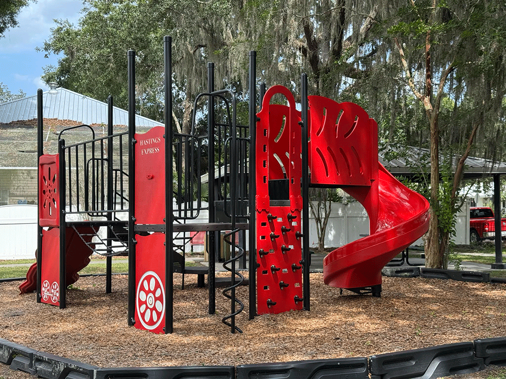 A small streetside playground in front of a covered pavilion