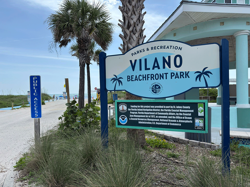 A sign for Vilano Beachfront Park with a beach access ramp in the background.