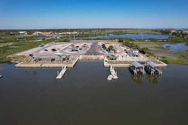 An aerial view of a large boat ramp, the adjacent parking lot, and the land beyond.