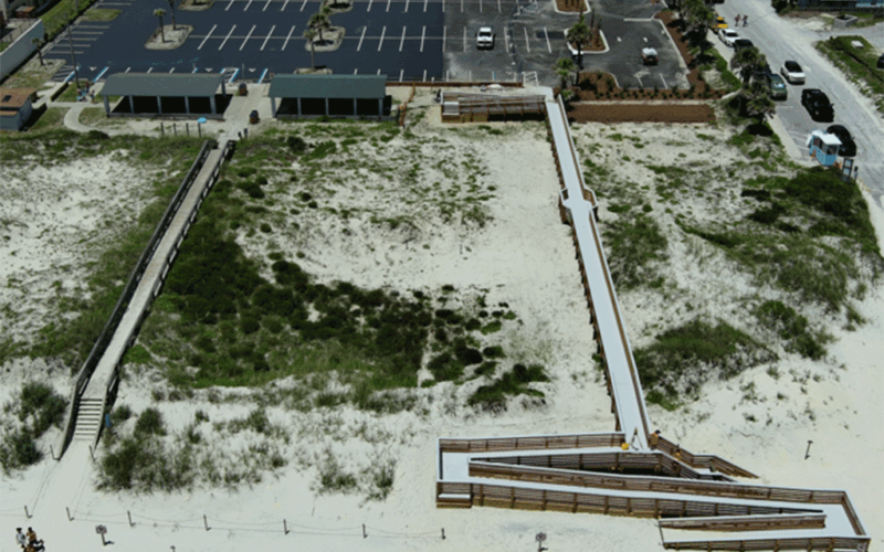 An aerial view of an ADA beach access ramp leading to the sand from a newly expanded parking lot.