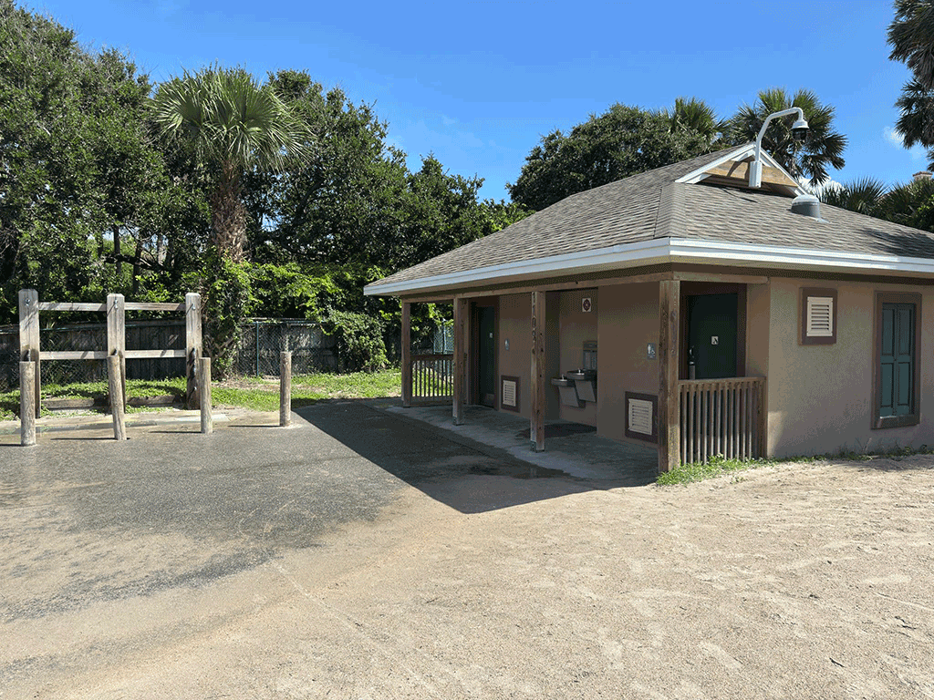 A restroom building next to showers and footbaths at a beachfront park.