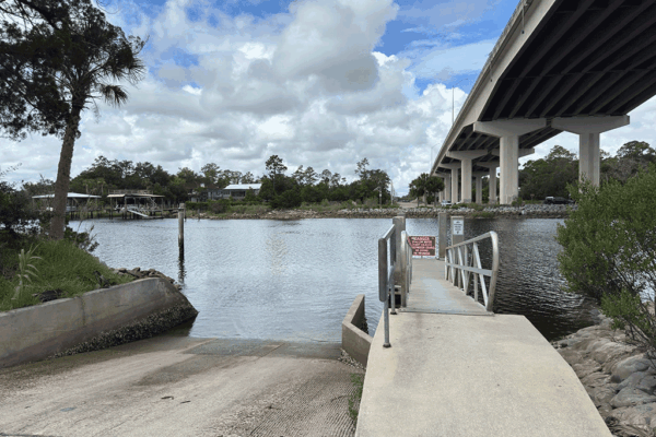 A boat ramp next to a floating dock under an overpass