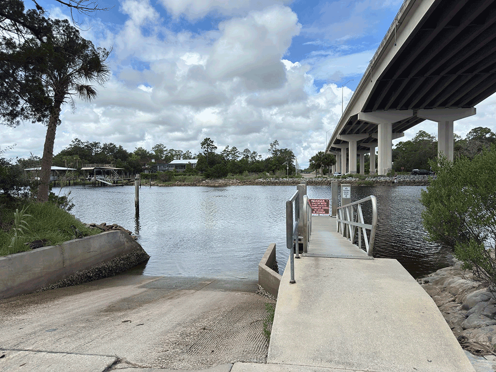 A boat ramp next to a floating dock under an overpass