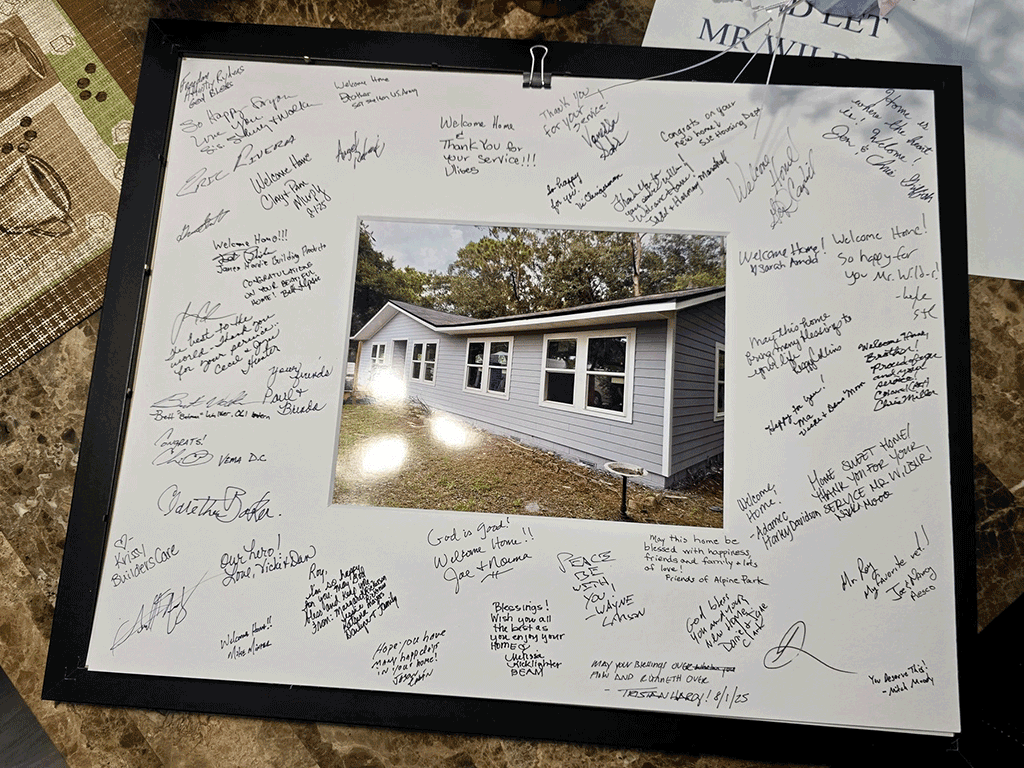 A framed image of the home surrounded by white paper with signatures and well wishes.