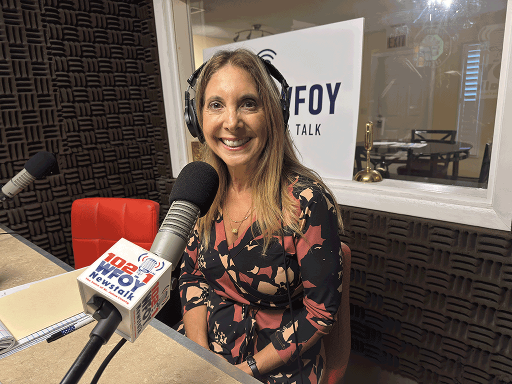 Commissioner Ann Taylor sits with headphones on in front of a microphone in a sound booth.