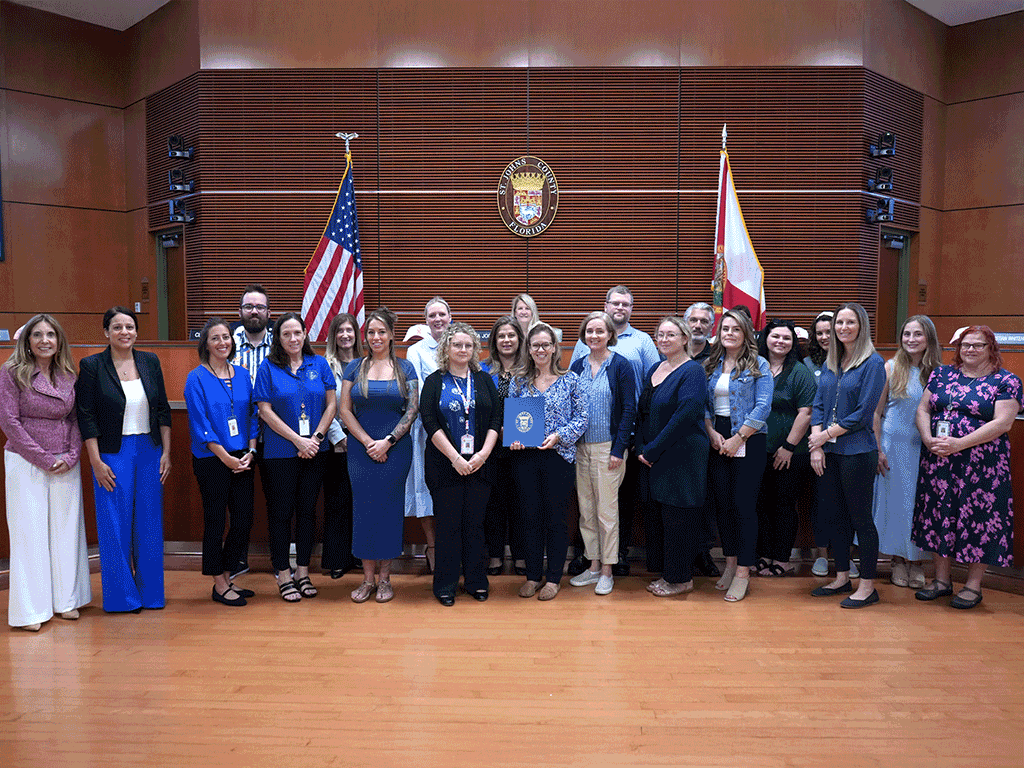 Commissioner Taylor stands with employees from Health and Human Services holding the proclamation.