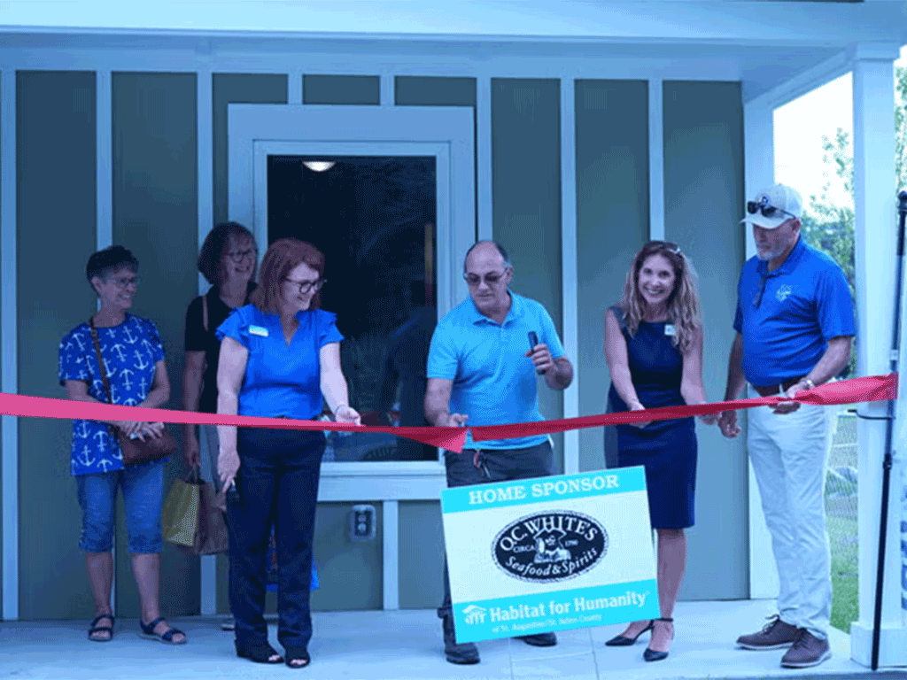 Commissioner Taylor and others cut the ribbon in front of a home for Habitat for Humanity.