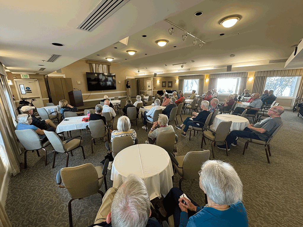 Commissioner Arnold speaks to a group of people at the Westminster Community in a formal dining area.