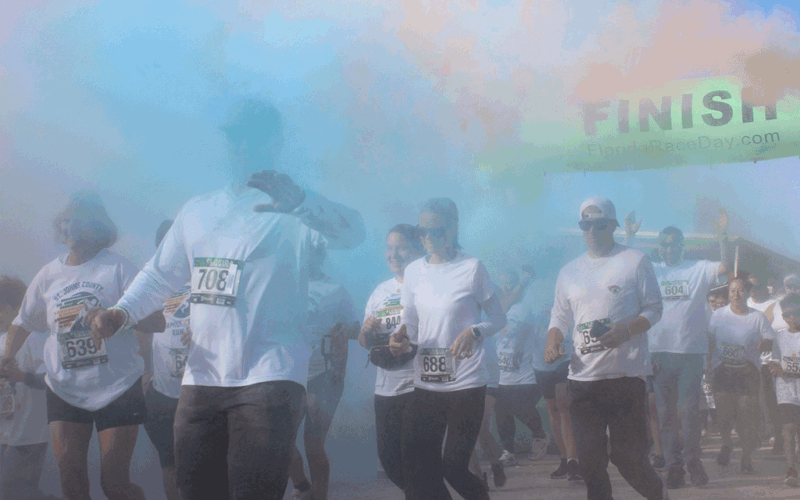 A crowd of runners dashes through multicolored clouds of smoke.
