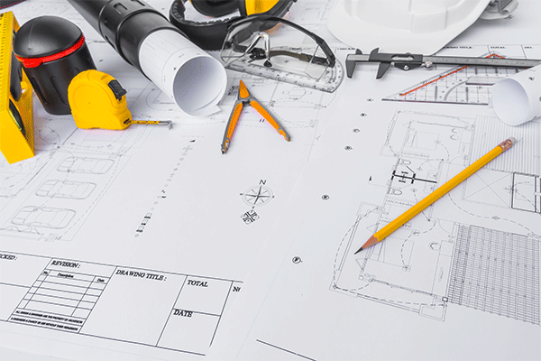 Construction blueprint drawings with pencils, compass, tape measure, and other tools.