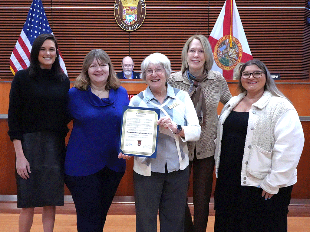 Commissioner Arnold stands with others and the proclamation presented for Human Trafficking Awareness Month