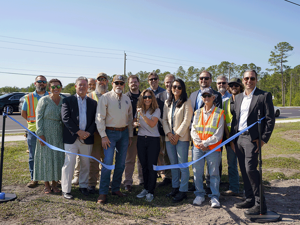 Commissioners and others stand in front of a cut ribbon