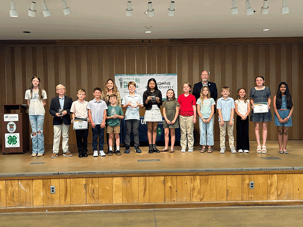 Commissioners Taylor and Murphy stand with children on a stage