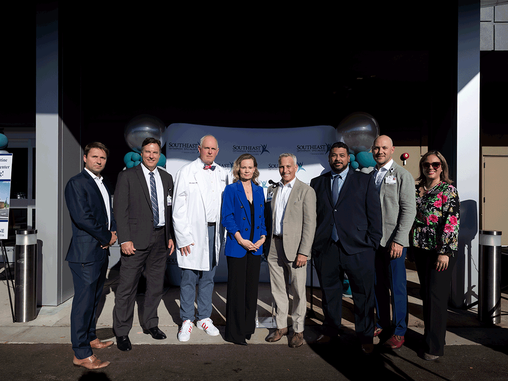 Healthcare leaders standing in front of a photo backdrop